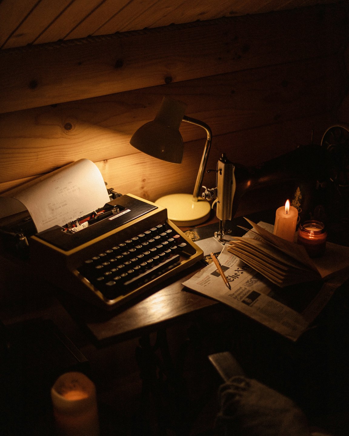 Vintage typewriter and sewing machine on a wooden desk.